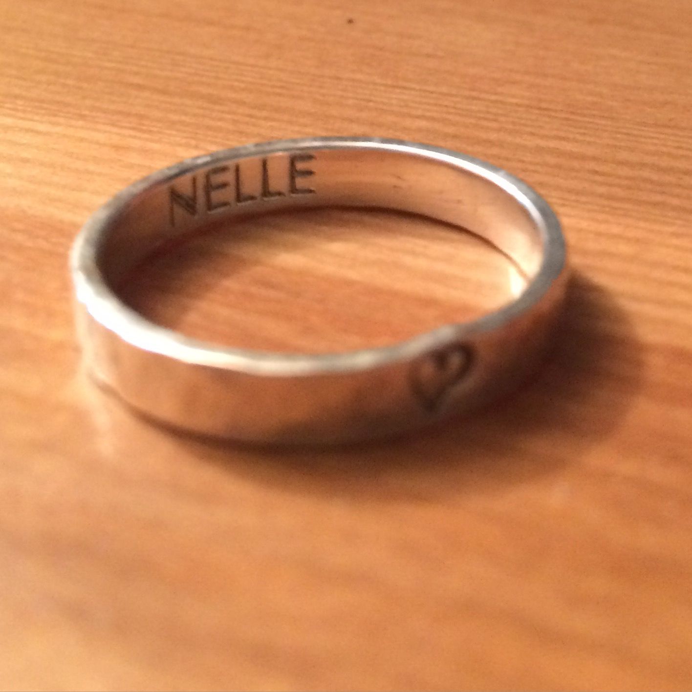 A silver ring inscribed with the word NELLE and a heart