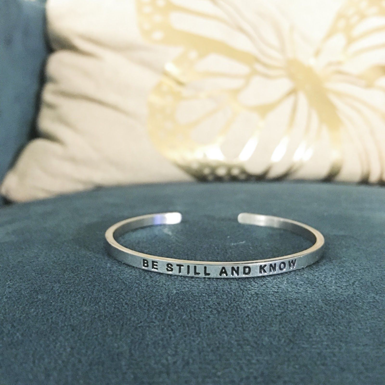 A silver bracelet engraved with the words "Be Still and Know"